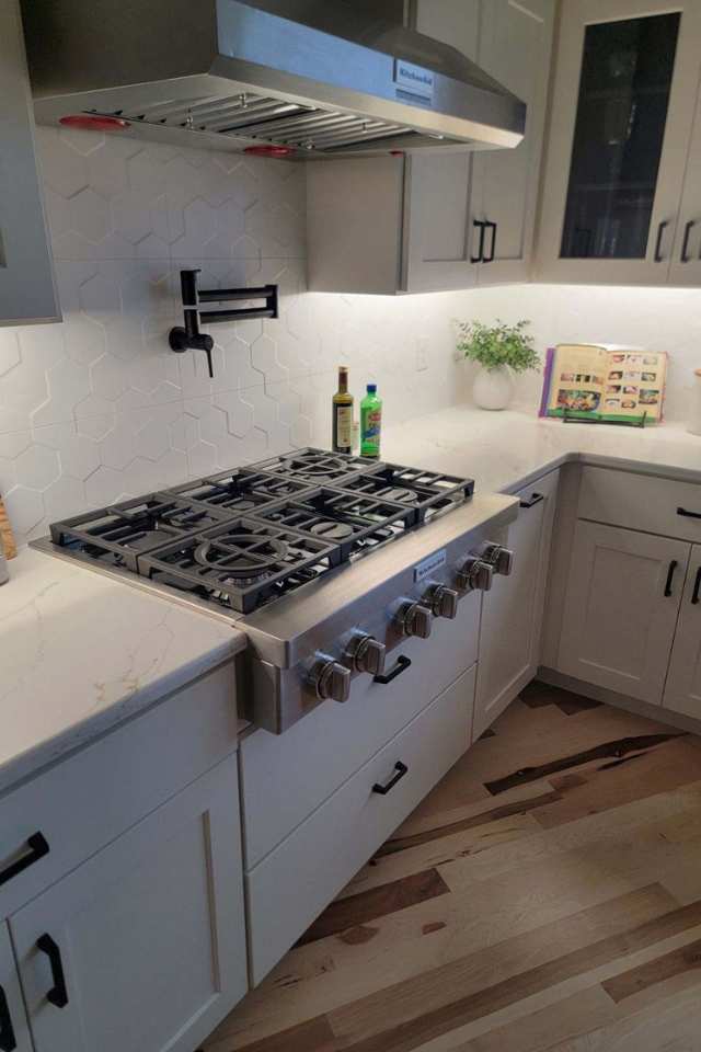 custom white geometric textured backsplash in modern kitchen with silver oven and black matte finishes